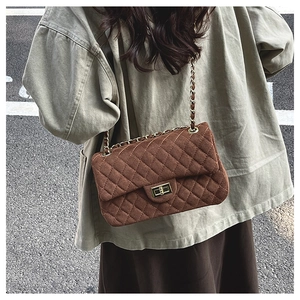 Detail of brown quilted suede bag showing golden twist lock and luxury chain strap