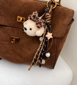 Primer plano de un llavero de oso de peluche con lazo de leopardo y cuerdas en un bolso
