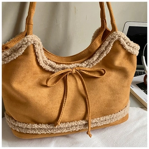Detail of suede tote bag featuring lamb wool trim and decorative bow in ginger yellow