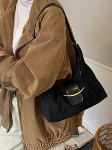 Sac cabas minimaliste noir en daim avec boucle dorée en croissant porté par un mannequin