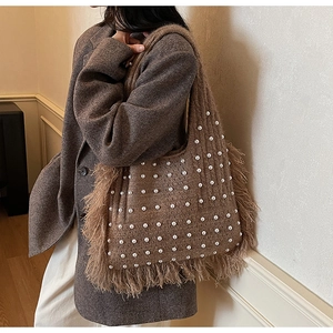 Detailed view of brown knit shoulder bag with white pearls and feather fringe tassels