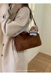 Detail view of large brown suede tote bag featuring contrast stitching and a cute bear charm