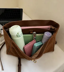 Detalle macro del interior espacioso del bolso tote de ante marrón con varios bolsillos