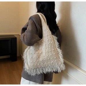 Detail of cream knit shoulder bag featuring white pearls and elegant long tassels