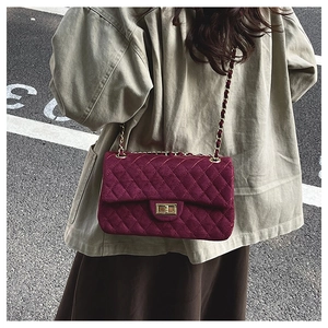 Close-up of burgundy quilted velvet chain bag with a gold metal twist-lock clasp
