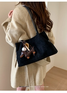 Detail of minimalist retro suede tote bag with cute sausage dog charm and slim shoulder straps
