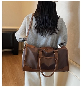 Deep brown nylon travel bag with leather trim and adjustable strap shown on model