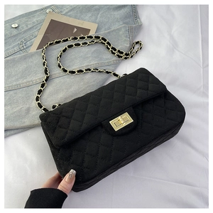 Close-up of black quilted suede shoulder bag with gold chain and twist-lock clasp