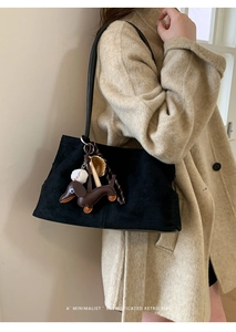 Detail of black suede tote bag with a dachshund leather charm and baseball keychain