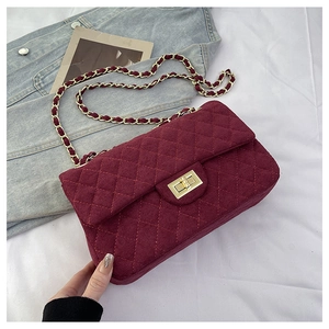 Detail of burgundy quilted suede shoulder bag featuring a gold chain strap and metal turn-lock
