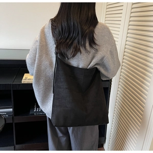 Minimalist black suede tote bag shown on model in a modern interior setting