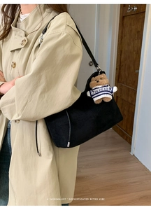 Close-up of black suede dumpling bag with cute bear charm and minimalist retro vibe