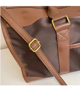 Detail of adjustable strap buckle and material stitching on brown crossbody bag