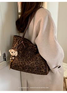 Close-up of leopard print tote bag with brown leather strap and plush bear charm