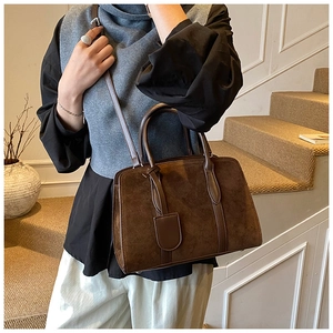 Gros plan d'un sac Boston rétro en daim marron foncé avec détail d'étiquette en cuir