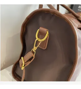 Close-up of golden metal hooks and precise stitching on dark brown travel handbag