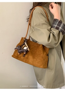 Detail of brown suede tote bag with cute dachshund and baseball pendant accessories
