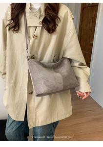 Close-up of minimalist grey suede crossbody bag with retro vibe and slim shoulder strap