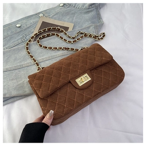 Detail of brown suede shoulder bag featuring quilted stitching and gold chain strap