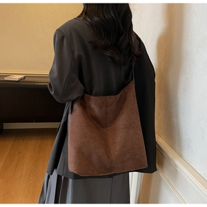 Detailed side view of a large brown suede tote bag showing its soft texture and capacity