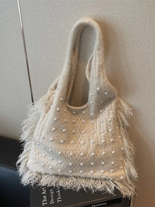 Elegant cream knit bucket bag featuring white pearls and lush feather tassels