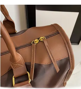 Detail of premium golden metal zippers and leather handles on a large travel duffel bag