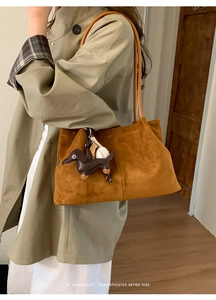 Brown faux suede tote bag with dog charm shown on shoulder with minimalist retro vibe