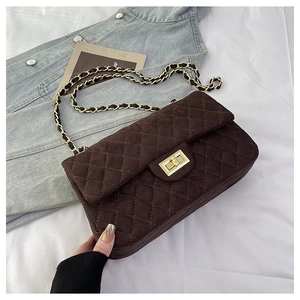 Detail of dark brown quilted chain bag with gold metal clasp and matte suede finish