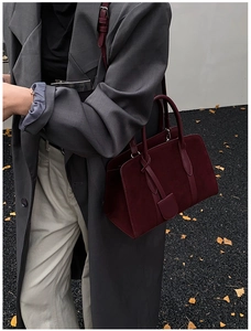 Détail du sac Boston en cuir dépoli bordeaux porté par un mannequin en décor d'automne