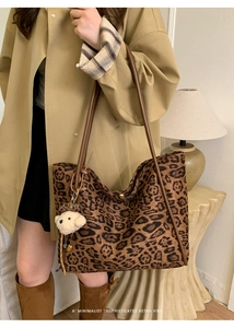 Detail of leopard print tote bag with brown straps and cute teddy bear charm pendant