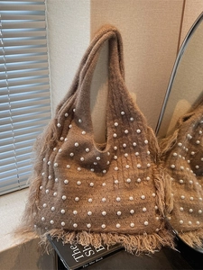 Brown knit bucket bag with pearl accents and fringe detail in a retro minimalist style