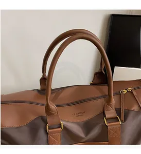 Detail of a brown duffle bag showing leather handles and IT CHICK EST-1988 print