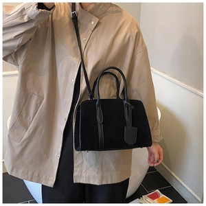 Vue détaillée du sac Boston noir en cuir mat avec deux poignées et bandoulière amovible