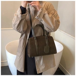 Détail d'un sac Boston en daim mat avec poignées en cuir et bandoulière réglable