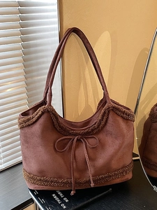 Brown suede tote bag with lamb wool trim and bow detail in a cozy interior scene