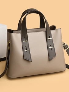 Minimalist khaki tote bag with contrast brown straps shown on a geometric pedestal