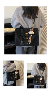 Detalle de bolso tote de ante negro con cierre dorado y colgante de oso de peluche