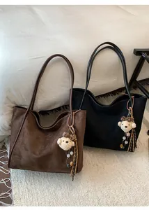 Close-up of vintage suede tote bags in black and brown with cute plush bear charms