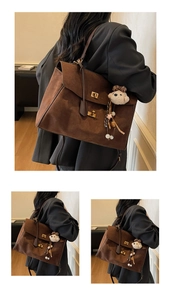 Detalle de bolso tote de ante café con cierres dorados y un colgante de oso de peluche