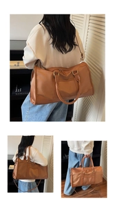Detail of caramel travel bag showing reinforced handles and adjustable shoulder strap