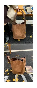 Dettaglio della borsa a secchiello in pelle scamosciata con manico intrecciato e finitura opaca