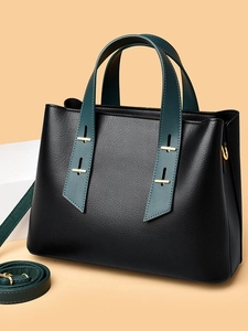 Minimalist black lychee leather tote bag with dark green straps and gold hardware