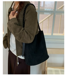 Détail du grand sac cabas en daim noir avec bandoulière tressée dans un cadre intérieur