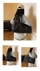 Detail of a large black nylon travel bag with reinforced handles and adjustable strap
