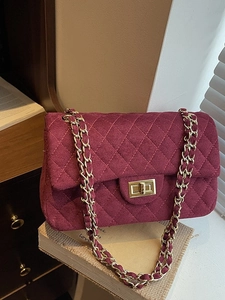 Burgundy suede shoulder bag with diamond quilting and gold chain strap in chic setting