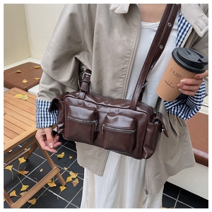 Macro view of a dark brown multi-pocket leather crossbody bag with vintage cargo styling