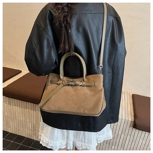 Brown suede baguette bag with buckle detail worn by a model in a side view