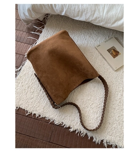 Dettaglio borsa hobo in camoscio marrone con tracolla in pelle intrecciata scura