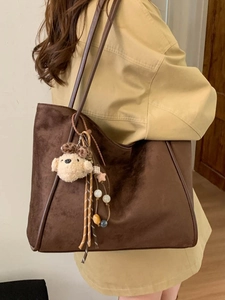 Deep brown oversized suede tote bag with plush charm shown worn on woman shoulder