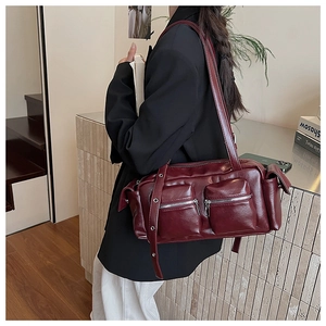 Close-up of wine red faux leather shoulder bag featuring multiple silver zipper pockets
